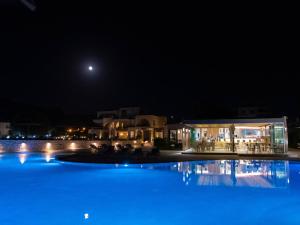 a swimming pool at night with the moon in the background at Kavos Hotel & Suites in Stavros