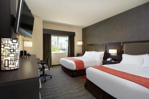 a hotel room with two beds and a flat screen tv at Holiday Inn Express & Suites Naples Downtown - 5th Avenue by IHG in Naples