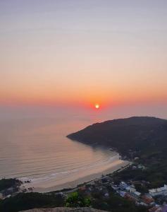 una puesta de sol sobre el océano y una playa en Recanto da Conceição, en Bombinhas