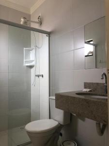 a bathroom with a toilet and a sink and a mirror at Gentil Hotel in Florianópolis