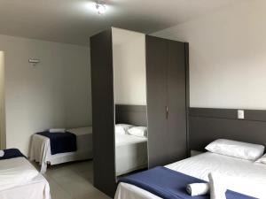1 Schlafzimmer mit 2 Betten und einem Schrank mit einem Spiegel in der Unterkunft Gentil Hotel in Florianópolis