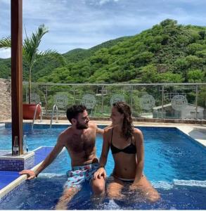 a man and a woman sitting in a swimming pool at Hostal Casa Roma in Taganga