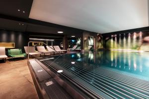una piscina en un hotel con sillas y una piscina en Hotel Chesa Monte 4Sterne Superior, en Fiss