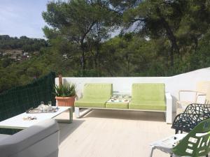 un patio con 2 sillas verdes y una mesa en Villa Paradise , playa climatizada y privada a 10 minutos de Sitges, en Sant Pere de Ribes