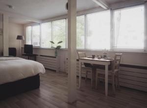 a bedroom with a table and a bed and windows at B&B Het Ruime Sop in Wassenaar