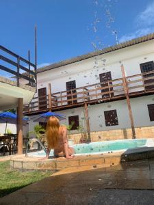 a woman sitting in a pool in front of a building at Convés Pousada in Barra de São Miguel