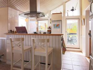 a kitchen with two stools at a counter with a refrigerator at 6 person holiday home in J gerspris in Frederikssund