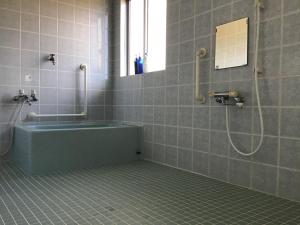 a bathroom with a tub and a shower with a mirror at Shimaotoya in Iriomote