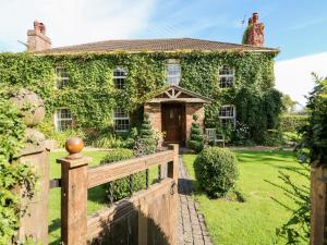 a house covered in ivy with a wooden fence at The Farmhouse in Skegness