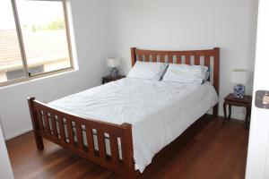 een slaapkamer met een bed met een houten frame en een raam bij Location @ Little Beach in Nelson Bay