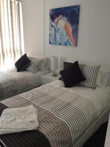 a bedroom with two beds and a painting on the wall at Broadwater Shores Waterfront Apartments in Gold Coast