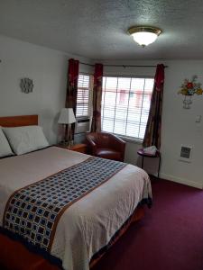 a hotel room with a bed and a chair at Holiday Motel Bend in Bend