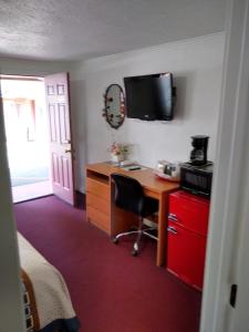 a room with a desk with a computer and a tv on the wall at Holiday Motel Bend in Bend