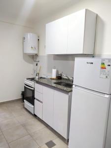 a kitchen with white cabinets and a refrigerator at Departamento Santo Tome centrico in Santo Tomé