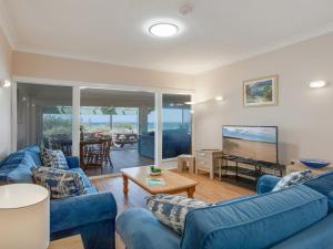 a living room with blue couches and a flat screen tv at Antonio's Paradise in Culburra Beach