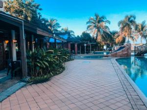 um resort com piscina e palmeiras em THE LAGOON WATER CHALET em Kampung Padang Masirat