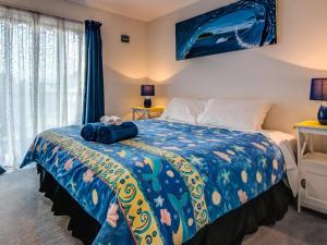 a bedroom with a bed with a blue comforter at Colonnades in Cape Woolamai