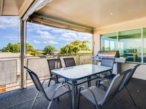a table and chairs on a balcony with a grill at Cuttriss by the Beach in Inverloch