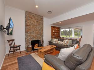 sala de estar con sofá y chimenea en Kinloch Cottage renovated to new on Daisy Hill Vineyard en Pokolbin