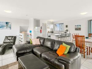 uma sala de estar com um sofá de couro e uma cozinha em Kahakai em Surf Beach