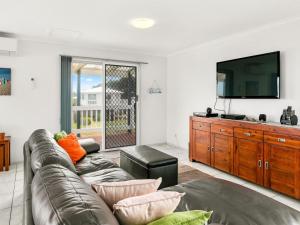 uma sala de estar com um sofá e uma televisão de ecrã plano em Kahakai em Surf Beach