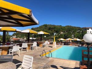 a swimming pool with chairs and tables and umbrellas at Flat Pipa's Ocean - Apto 319 in Pipa