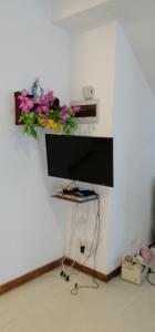 a flat screen tv hanging on a wall with flowers at Weeraman's Vila in Kadawata