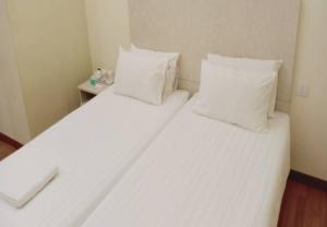 two beds in a room with white sheets and pillows at 1ACS Residence in Kuching