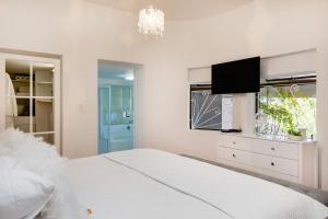 biała sypialnia z dużym łóżkiem i telewizorem z płaskim ekranem w obiekcie Incredible Cape Town Corner w Kapsztadzie