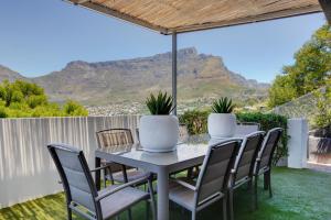 una mesa y sillas en un patio con montañas al fondo en Incredible Cape Town Corner, en Ciudad del Cabo