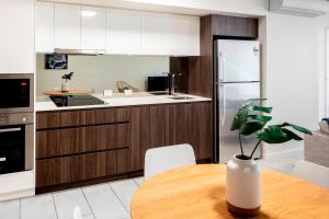 a kitchen with a table and a refrigerator at First Light Mooloolaba in Mooloolaba