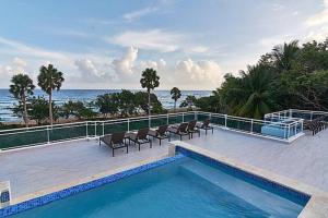 a swimming pool with chairs and the ocean in the background at Best ocean view Sosua-Cabarete in Sosúa