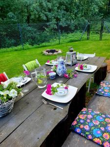 uma mesa de madeira com pratos de comida e flores em Szary Domek 1 jacuzzi komienk sauna klimatyzacja jezioro em Piotrków Kujawski