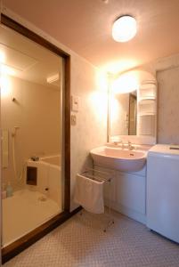 a bathroom with a sink and a mirror and a tub at Hakuba Inn Bloom in Hakuba