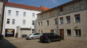 twee auto's geparkeerd op een parkeerplaats naast een gebouw bij Hostel Vorharz Aschersleben in Aschersleben