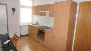 - une cuisine avec des placards en bois, un évier et une cuisinière dans l'établissement Hostel Vorharz Aschersleben, à Aschersleben