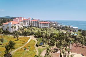 een luchtzicht op een resort met palmbomen en de oceaan bij Sono Calm Jeju in Seogwipo