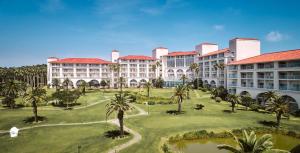 an aerial view of the courtyard of a resort with palm trees at Sono Calm Jeju in Seogwipo