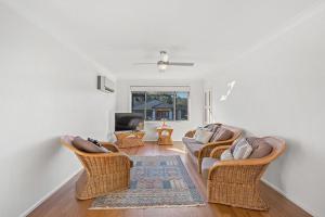 a living room with wicker chairs and a couch at Location @ Little Beach in Nelson Bay