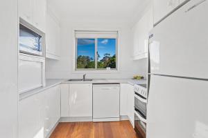 a white kitchen with a sink and a refrigerator at Location @ Little Beach in Nelson Bay