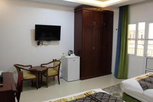 a hotel room with a table and a tv and a room at Al Diyar Hotel in Nizwa