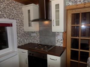 cocina con armarios blancos y fogones en Jane's Cottage Free Parking, en Inverness