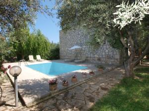 a swimming pool with potted plants next to a stone wall at Gerolakos Country Houses in Stavromenos