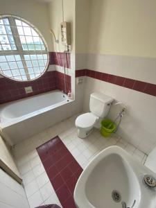 a bathroom with a toilet and a tub and a sink at Marina Apartment 3R2B in Kampong Baharu