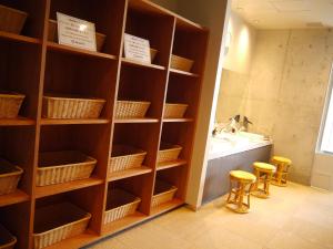 baño con estanterías de madera, lavamanos y 2 taburetes en HEARTS Capsule Hotel & Spa HAKATA, en Fukuoka