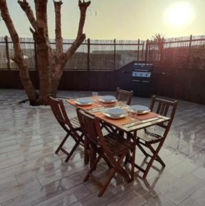 uma mesa de madeira com quatro cadeiras em Romántico apartamento, piscina y BBQ en Playa La Tejita em El Médano