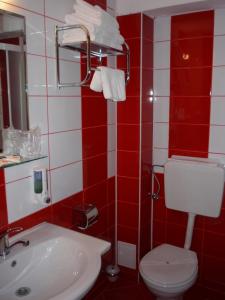 a red and white bathroom with a toilet and a sink at Hotel Sud in Giurgiu