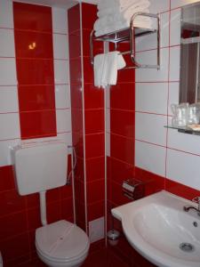 a red and white bathroom with a toilet and a sink at Hotel Sud in Giurgiu