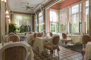 um restaurante com mesas e cadeiras brancas e janelas em Belle Isle Sur Risle - Chateau Hotel & Spa em Pont-Audemer