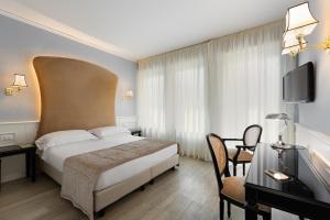 Cette chambre comprend un lit, un bureau et une télévision. dans l'établissement Hotel San Luca, à Vérone
